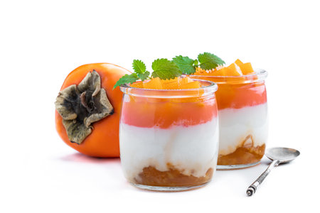 White  fruity yogurt in glass jar with fresh persimmon isolated on whiteの写真素材