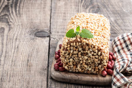 Sponge cake roll covered with nuts on wooden tableの写真素材