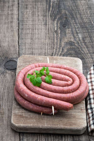 Raw thin lamb sausages on wooden tableの写真素材