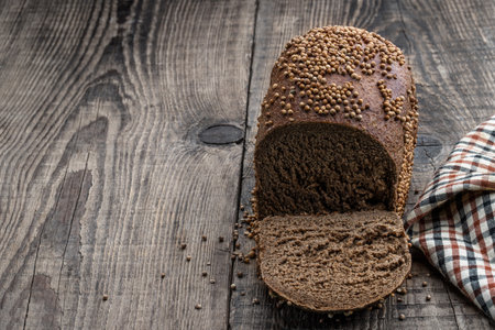 Homemade dark rye bread with coriander seeds on wooden tableの写真素材