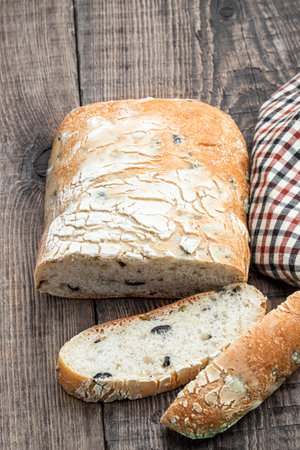 Freshly baked Italian ciabatta with olives on wooden table