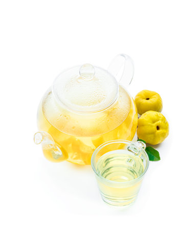 Hot quince tea in transparent teapot with fresh fruits isolated on whiteの写真素材