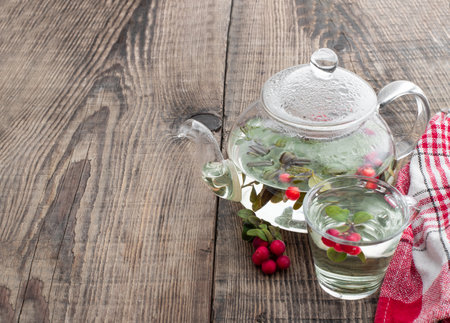Tasty lingonberry tea in teapot on wooden tableの写真素材