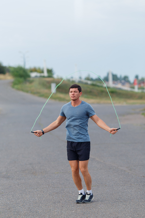 Portrait of young male athlete skipping rope outdoorsの写真素材