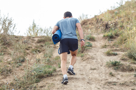 A young man walking on the trail. travel sport lifestyle concept. view from the backの写真素材