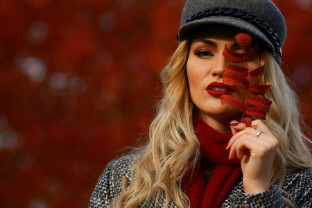 Portrait of beautiful young woman with autumn leafs. Red maple garden background.