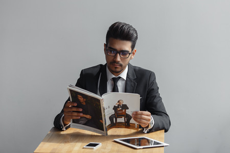 young, rich, handsome, bearded man, a successful businessman reading a magazine in a cafeの写真素材