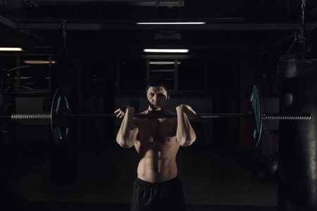 The clean and jerk exercise - young man doing weightlifting workout at the gym