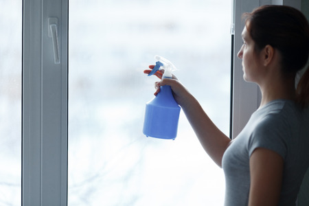 The young girl carefully washes and cleans a windowの写真素材