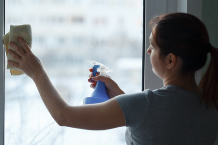 The young girl carefully washes and cleans a window