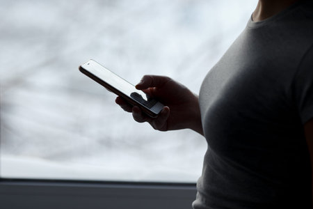 woman hands using mobile, smart phone at glass window house background