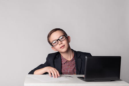 Portrait of young business boy in glasses at the laptopの写真素材