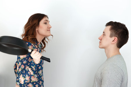 Funny family couple, woman with a frying pan scolding man, humor on 8 march. International womens...
