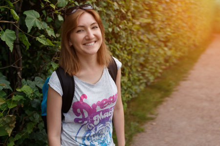Close up portrait of a young woman with a backpack, sunlight.