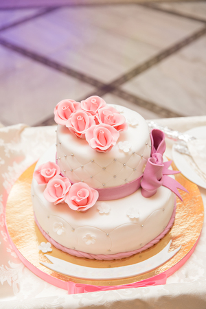 White wedding cake on wedding banquet with red rose and other flowers.の写真素材