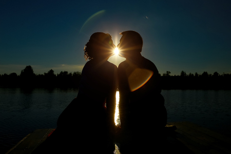 couple in love backlight silhouette at lake. Silhouette of couple kissing at sunset.の写真素材