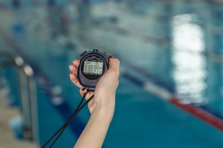 Close-up of coach hand holding stopwatch at poolside.の写真素材