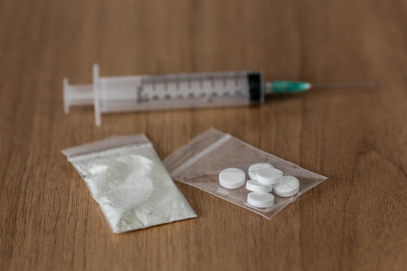 spoon, plastic packet with cocaine and syringe on the wooden table. Concept stop drug addiction.の写真素材