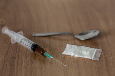 spoon, plastic packet with cocaine and syringe on the wooden table. Concept stop drug addictionの写真素材