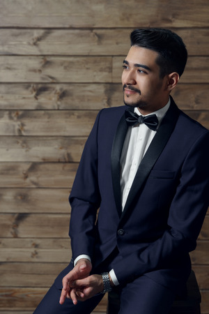 Portrait of young beautiful fashionable man on wooden background.の写真素材