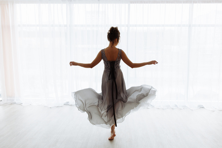 Sexy woman in transparent dress against window, back view, room in white tones on backgroundの写真素材