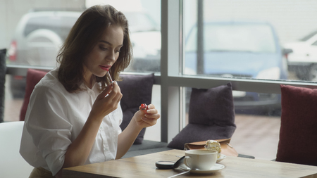 Business woman refreshing make-up after lunch break in cafeの写真素材