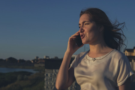 Serious girl talking on phone on the sunset. copyspaceの写真素材