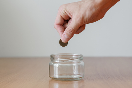 Hand putting money coin in to the empty glass jar. Future investment concept. Donation boxの写真素材