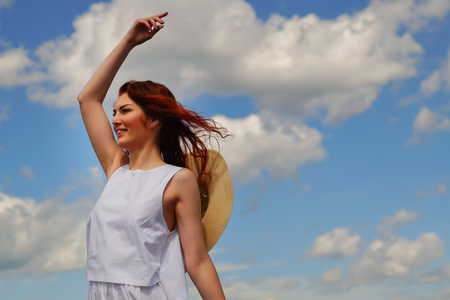 Young woman with beautiful red hair, blue cloudy sky on backgroundの写真素材