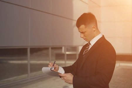 attractive businessman considering contract for signature on background of business building, sunlightの写真素材