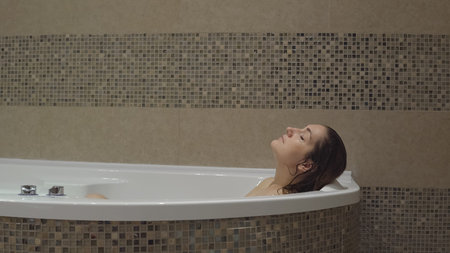 Cute young woman washing and relaxing in the bathroom after hard day's work