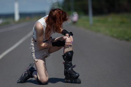 young woman fell on the road and bruised her knee during skatingの写真素材