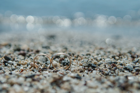 wedding rings on the pebble sand on the beach, copy space. selective focusの写真素材