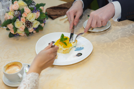 The newlyweds at the table are drinking coffee and eating dessert.の写真素材