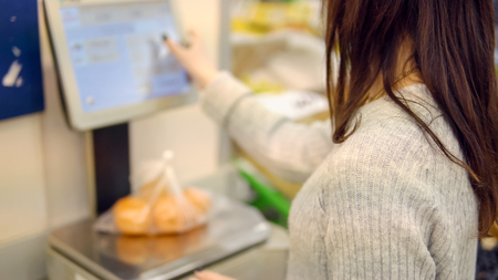 Young woman in the vegetable department of a supermarket weighs tangerines.の写真素材