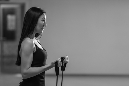 Fitness girl performs exercises with expander. Strength and motivationの写真素材