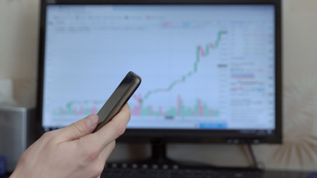 Man with phone in hands on computer monitor background.の写真素材