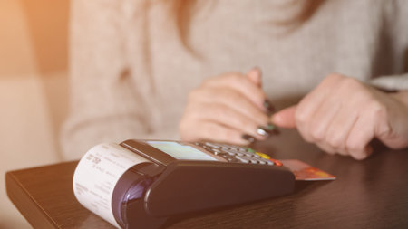 Cashless payment. A woman pays in a cafe through the terminal, sunlight
