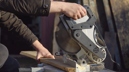 strong man saws boards with a circular saw.