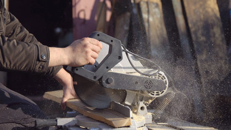 Man saws boards with a circular saw, hard work