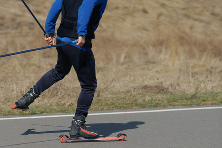 man on summer skis is riding on an asphalt road.の写真素材