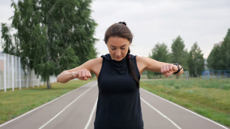 Pretty sporty girl stretching arms on treadmill of stadium.の写真素材