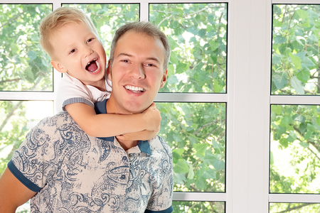 portrait of a happy father carrying young boy on back at home, close upの写真素材