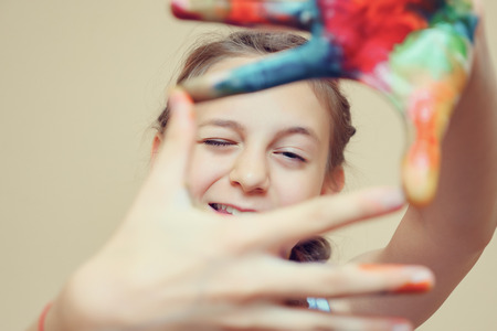 Teenage girl outstretching hands in paints making focus frame looking at camera, tonedの写真素材