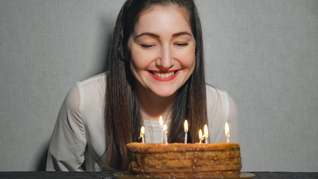 Happy Emotional Girl Blows out Candles During Celebration Her Birthday and Applauds, close up.の写真素材