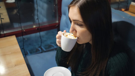 Attractive girl in a cafe drinking coffee, close-up.の写真素材