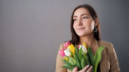 Beautiful girl with a bouquet of tulips, enjoy and looking out the window. copy space