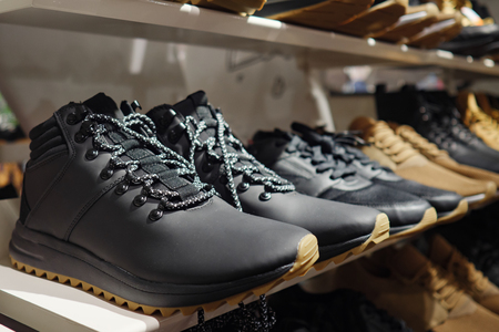 Row of contemporary stylish sneakers of brown and black colors arranged on shelf in clothes storeの写真素材