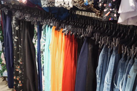 Metal rack with hangers of colorful fashionable trousers in contemporary shop, close upの写真素材