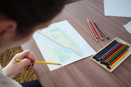 young woman drawing on paper at home, top viewの写真素材